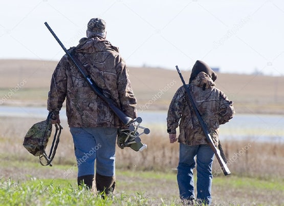 Two hunters walking in a field with guns — stock photo.