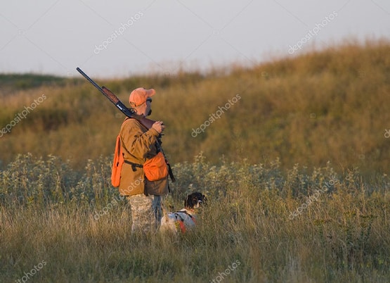 A pheasant hunter with a rifle and a pheasant in the field — stock photo.