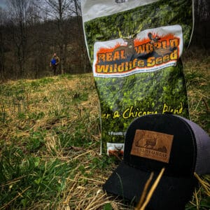 A bag of wildflower seeds and a hat on a grassy field.